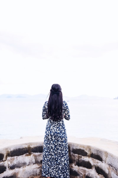 女人穿着黑色和白色的长袖连衣裙站面临海洋白天
